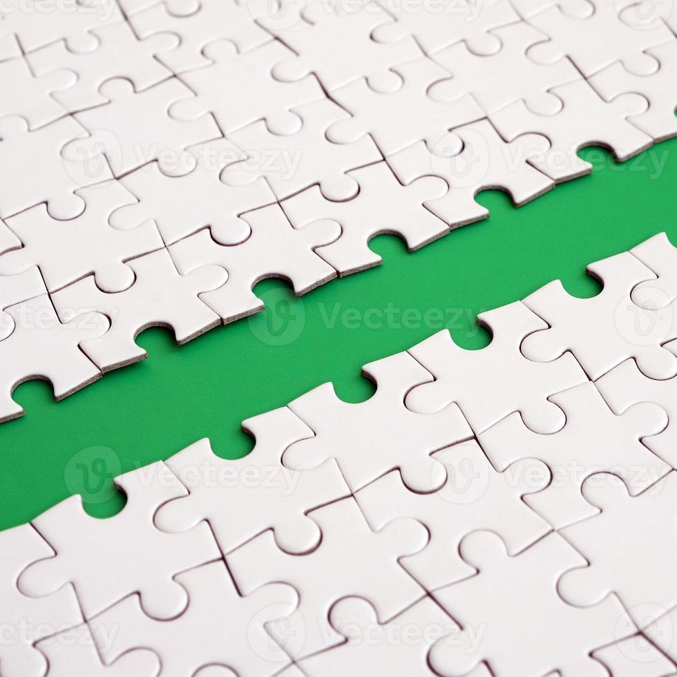 The green path is laid on the platform of a white folded jigsaw puzzle. Texture image with copy space for text photo