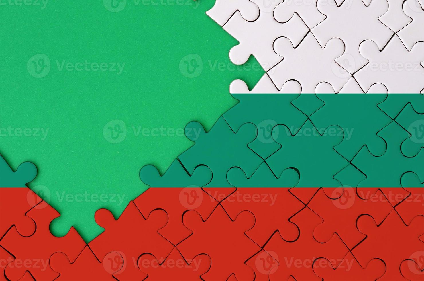 Bulgaria flag is depicted on a completed jigsaw puzzle with free green copy space on the left side photo