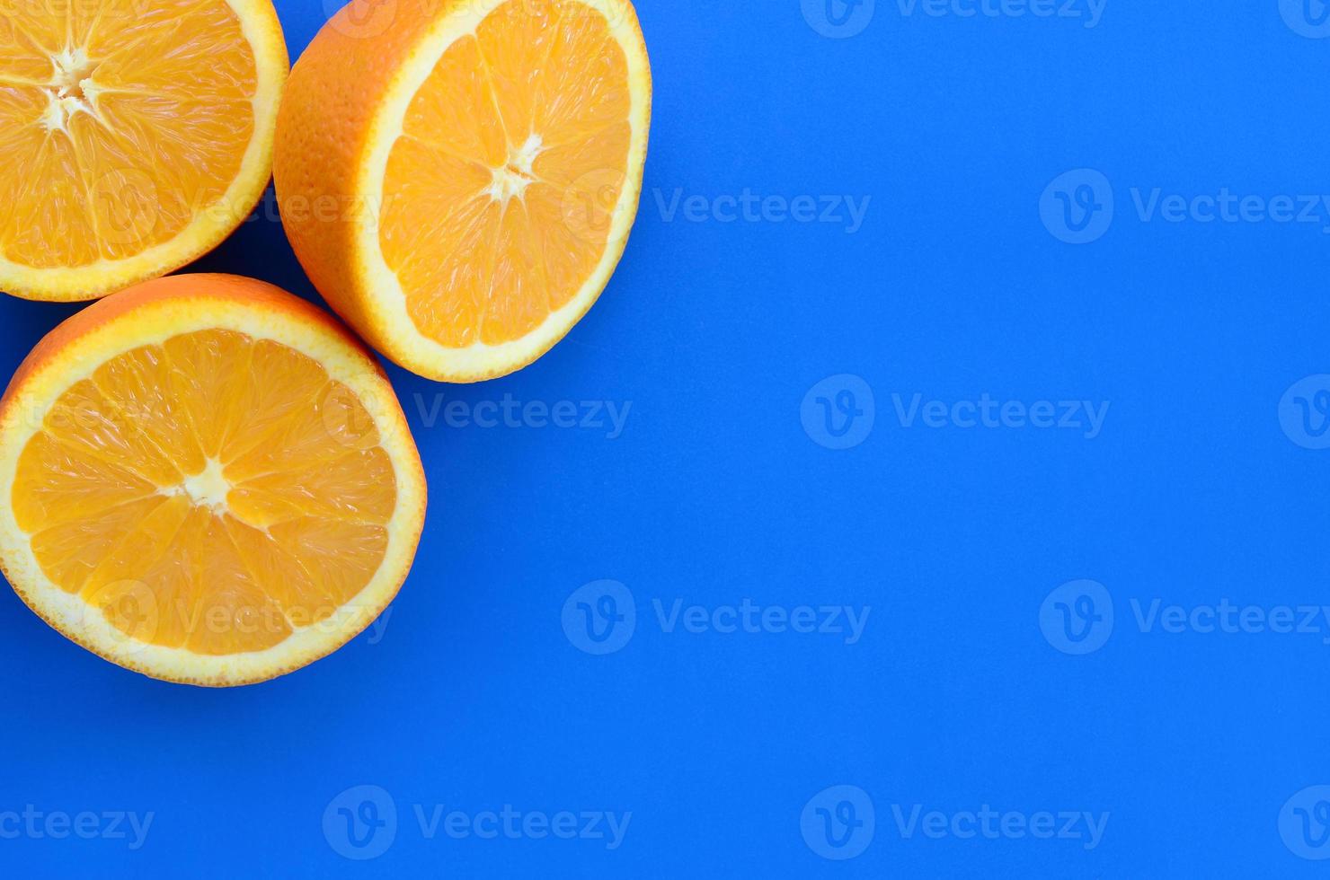 Top view of a several orange fruit slices on bright background in blue color. A saturated citrus texture image photo