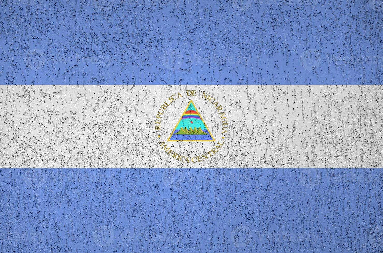 Nicaragua flag depicted in bright paint colors on old relief plastering wall. Textured banner on rough background photo