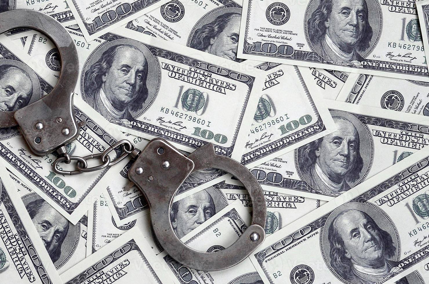 Police handcuffs lie on a lot of dollar bills. The concept of illegal possession of money, illegal transactions with US dollars. Economic Crime photo