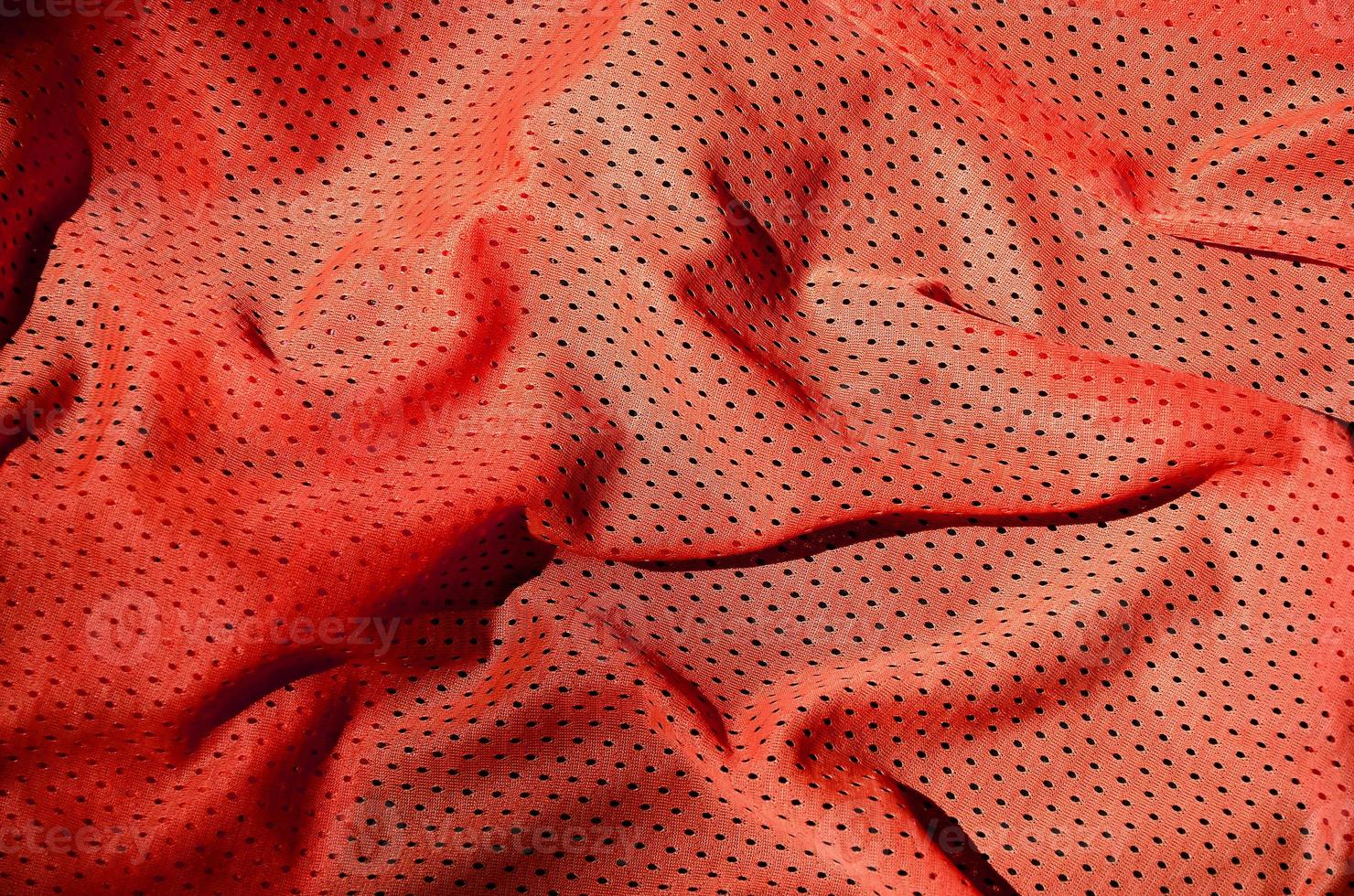 Sport clothing fabric texture background. Top view of red polyester nylon cloth textile surface. Colored basketball shirt with free space for text photo