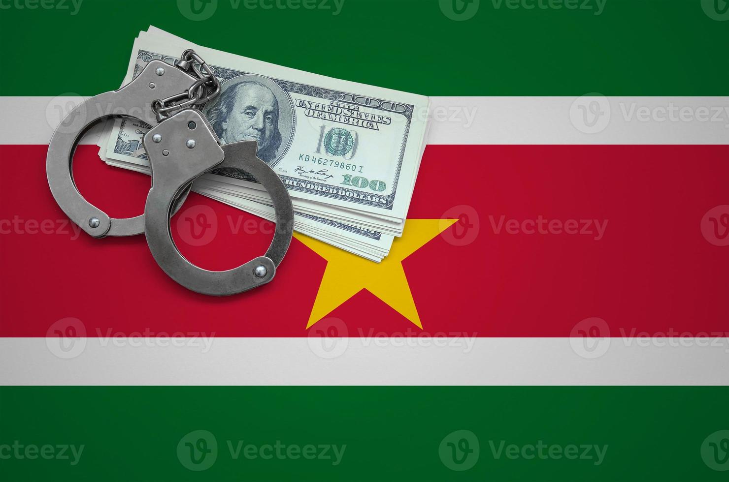 Suriname flag with handcuffs and a bundle of dollars. The concept of breaking the law and thieves crimes photo