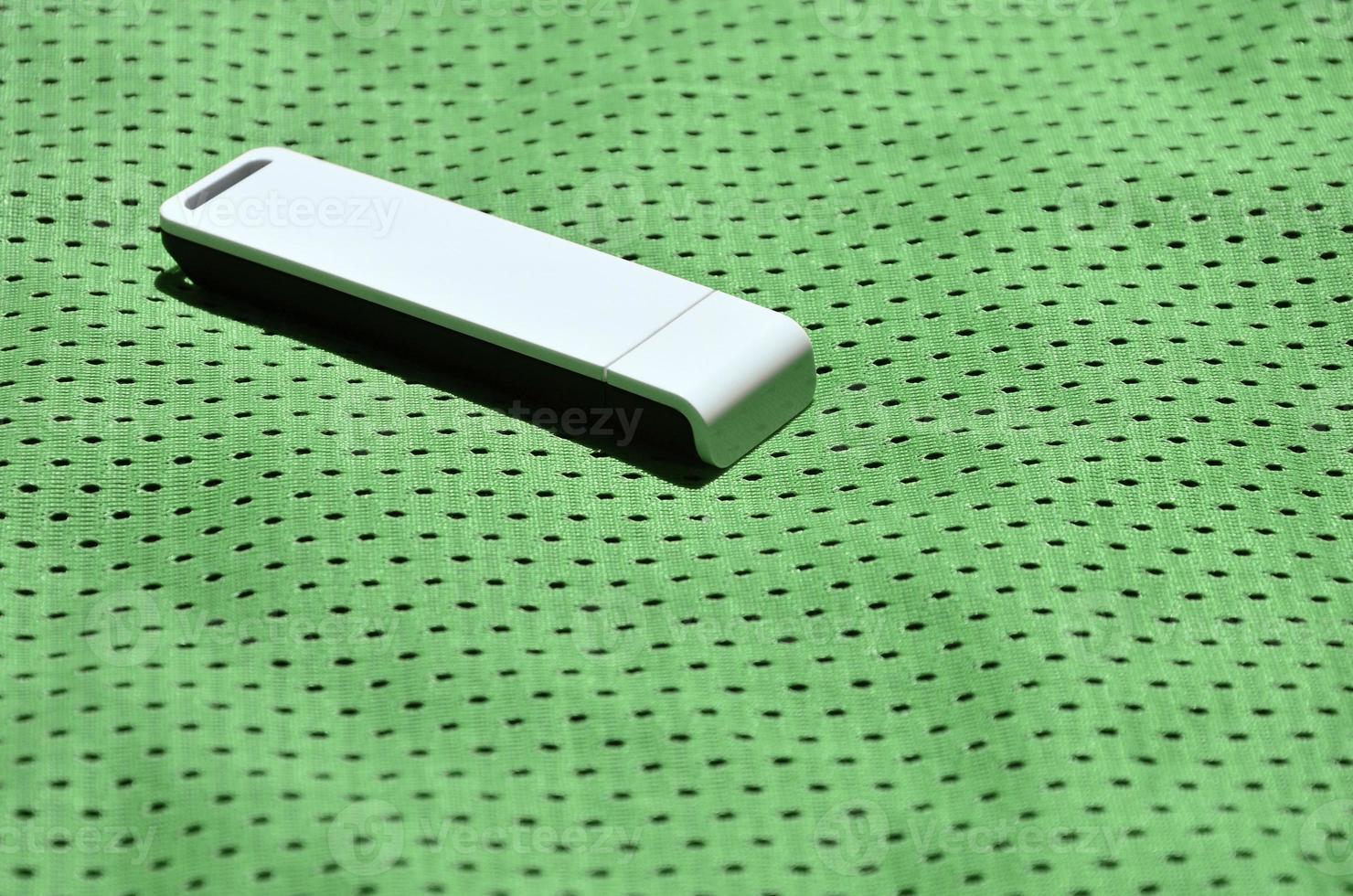 A modern portable USB wi-fi adapter is placed on the green sportswear made of polyester nylon fiber photo