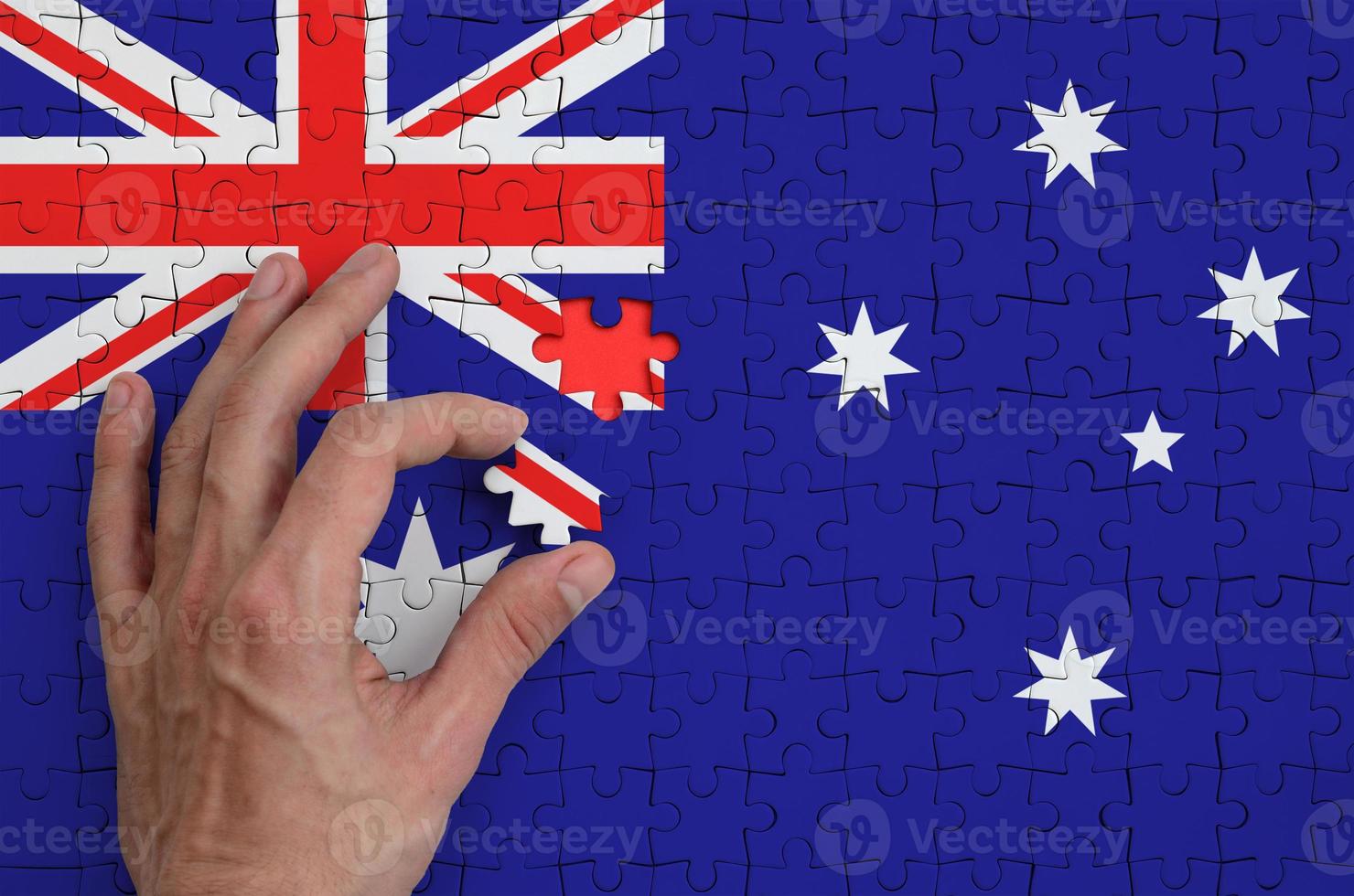 Australia flag is depicted on a puzzle, which the man's hand completes to fold photo