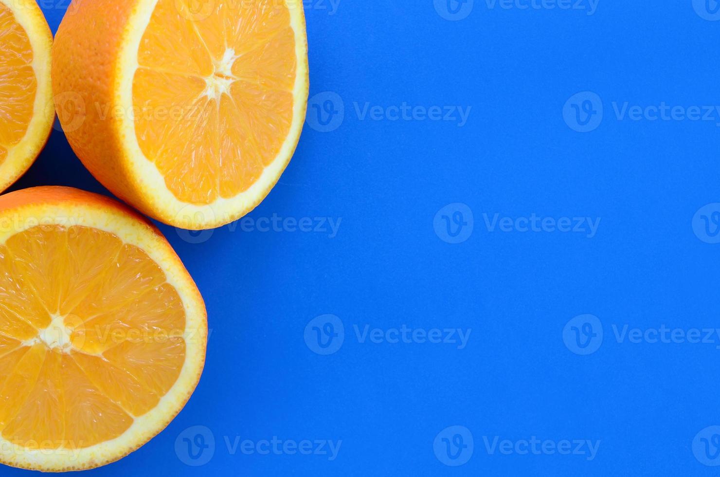 Top view of a several orange fruit slices on bright background in blue color. A saturated citrus texture image photo