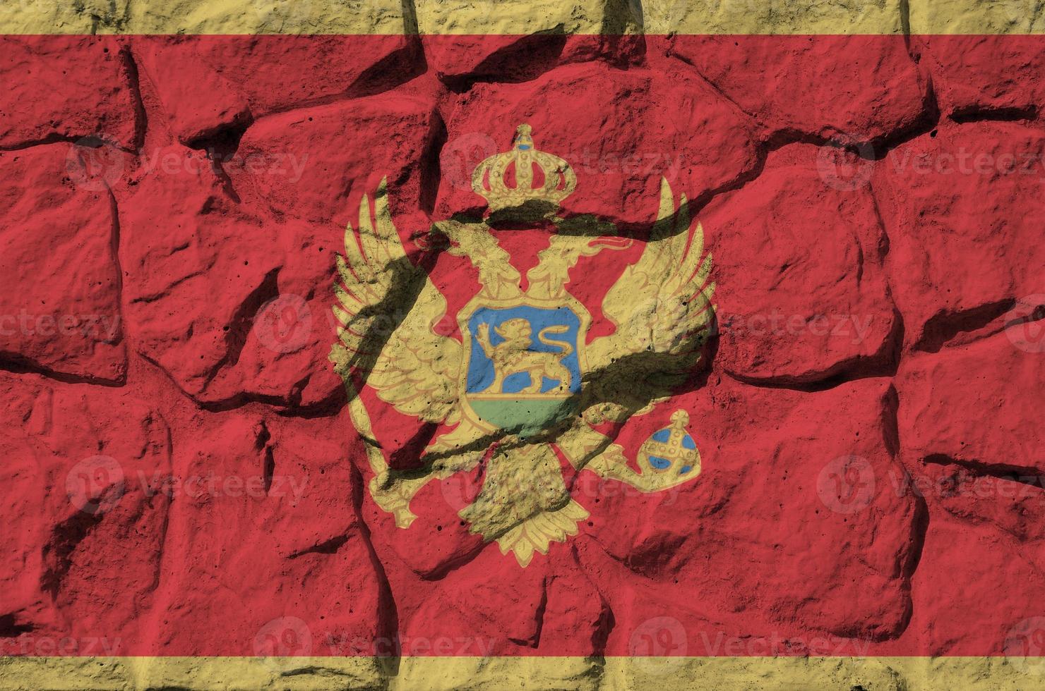 Montenegro flag depicted in paint colors on old stone wall closeup. Textured banner on rock wall background photo