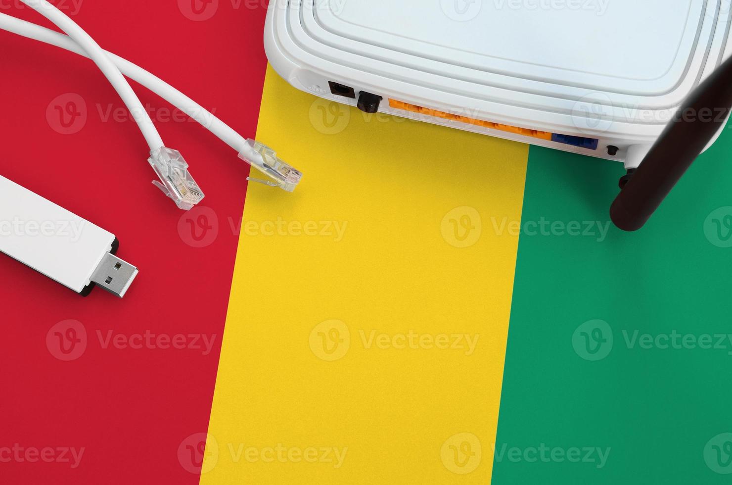 Guinea flag depicted on table with internet rj45 cable, wireless usb wifi adapter and router. Internet connection concept photo