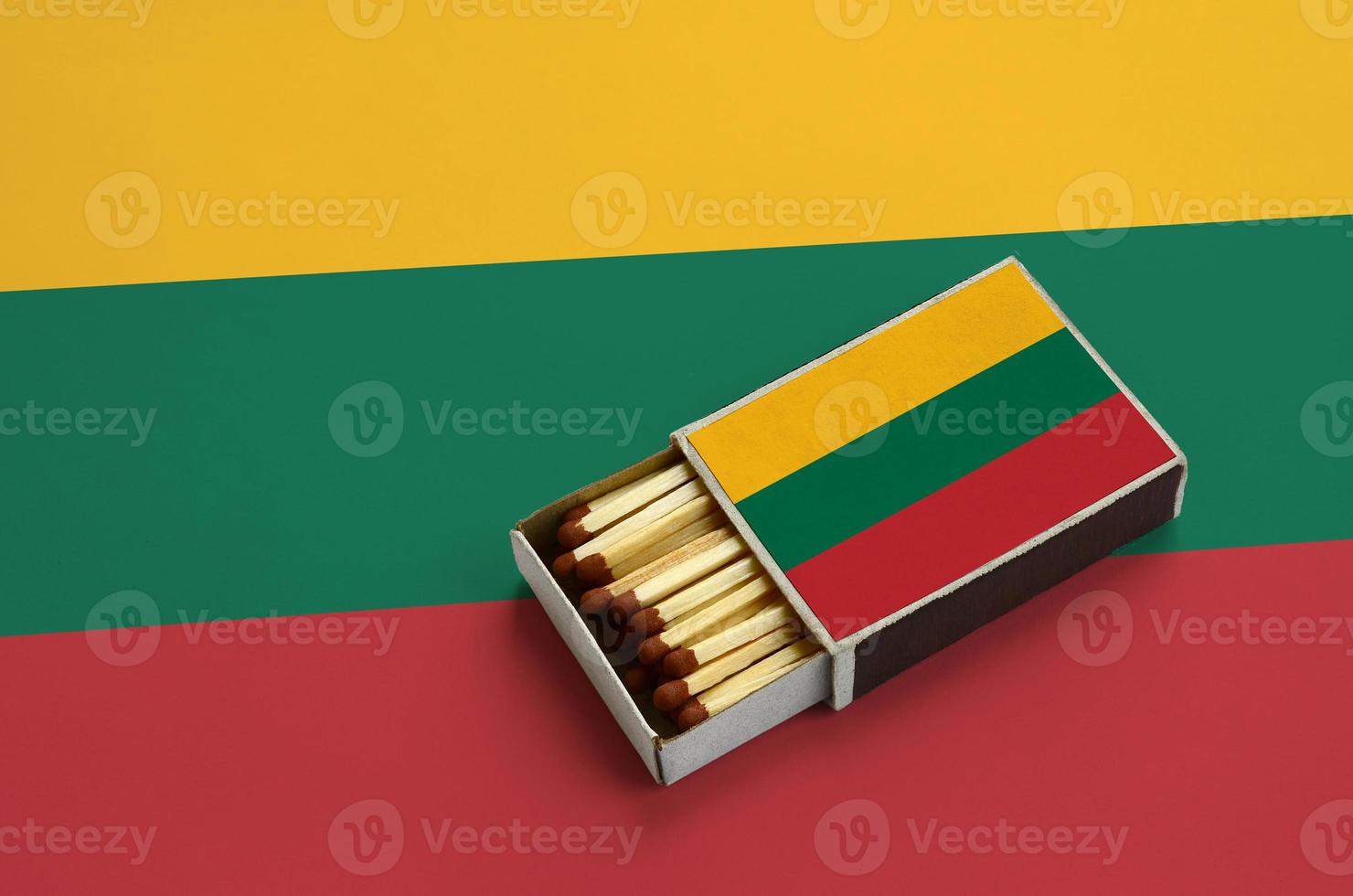 Lithuania flag is shown in an open matchbox, which is filled with matches and lies on a large flag photo
