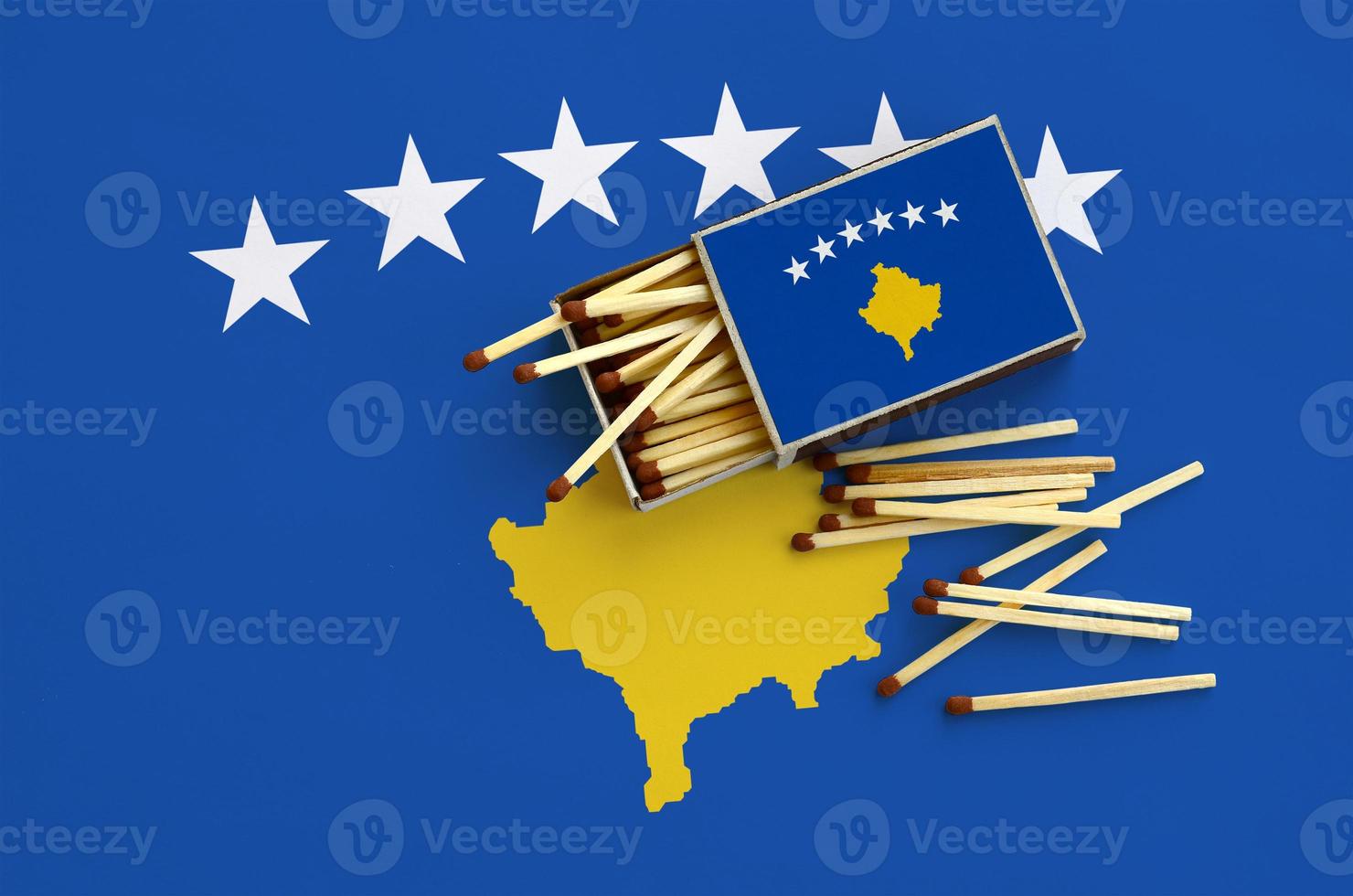 Kosovo flag is shown on an open matchbox, from which several matches fall and lies on a large flag photo