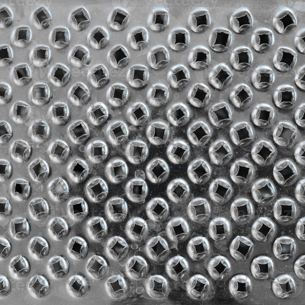 A fragment of a metal chrome grater close-up. Texture of blades for grinding food photo