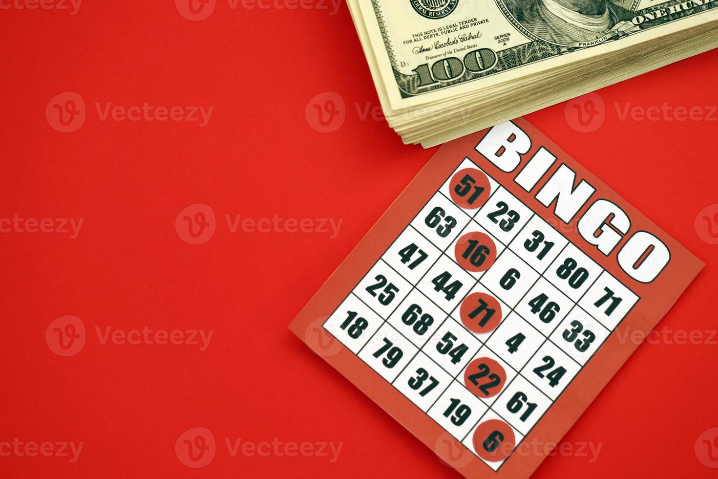 Red bingo board or playing card for winning chips and stack of dollar bills. Classic american or canadian five to five bingo card on red background photo