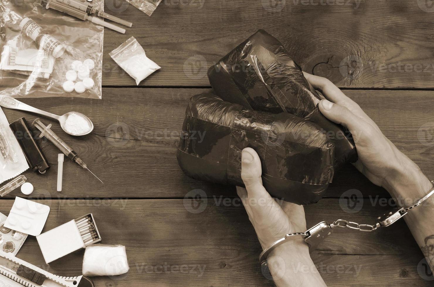 Drug trafficker arrested with their heroin packages. Police arrest drug dealer with handcuffs and many narcotic stuff on wooden table photo