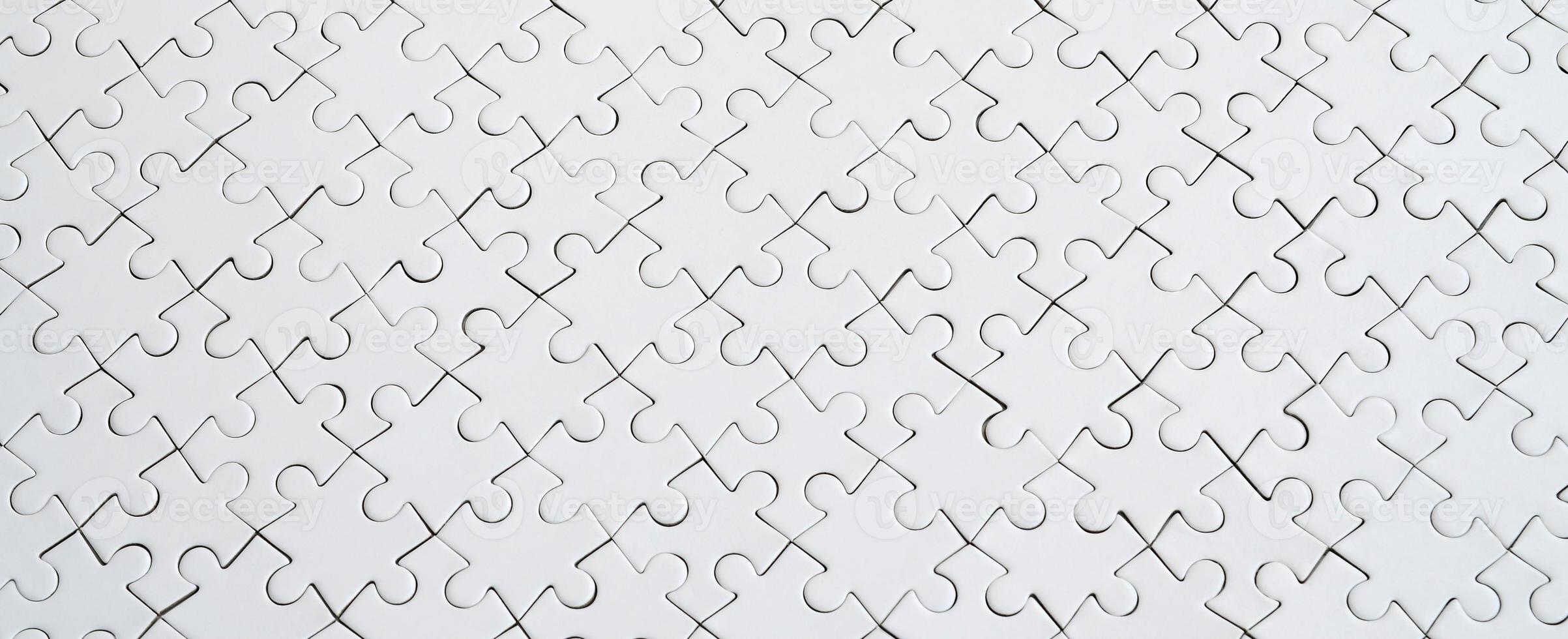 Close up texture of a white jigsaw puzzle in assembled condition. Top view. Many components of a large whole mosaic are united photo