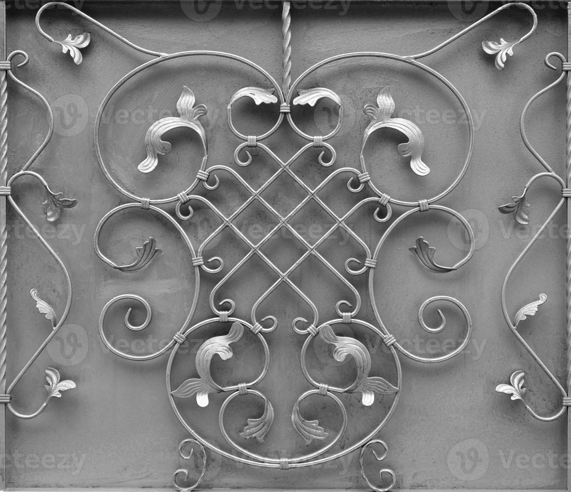 The texture of the silver metal gate with a beautiful floral pattern of forged metal photo