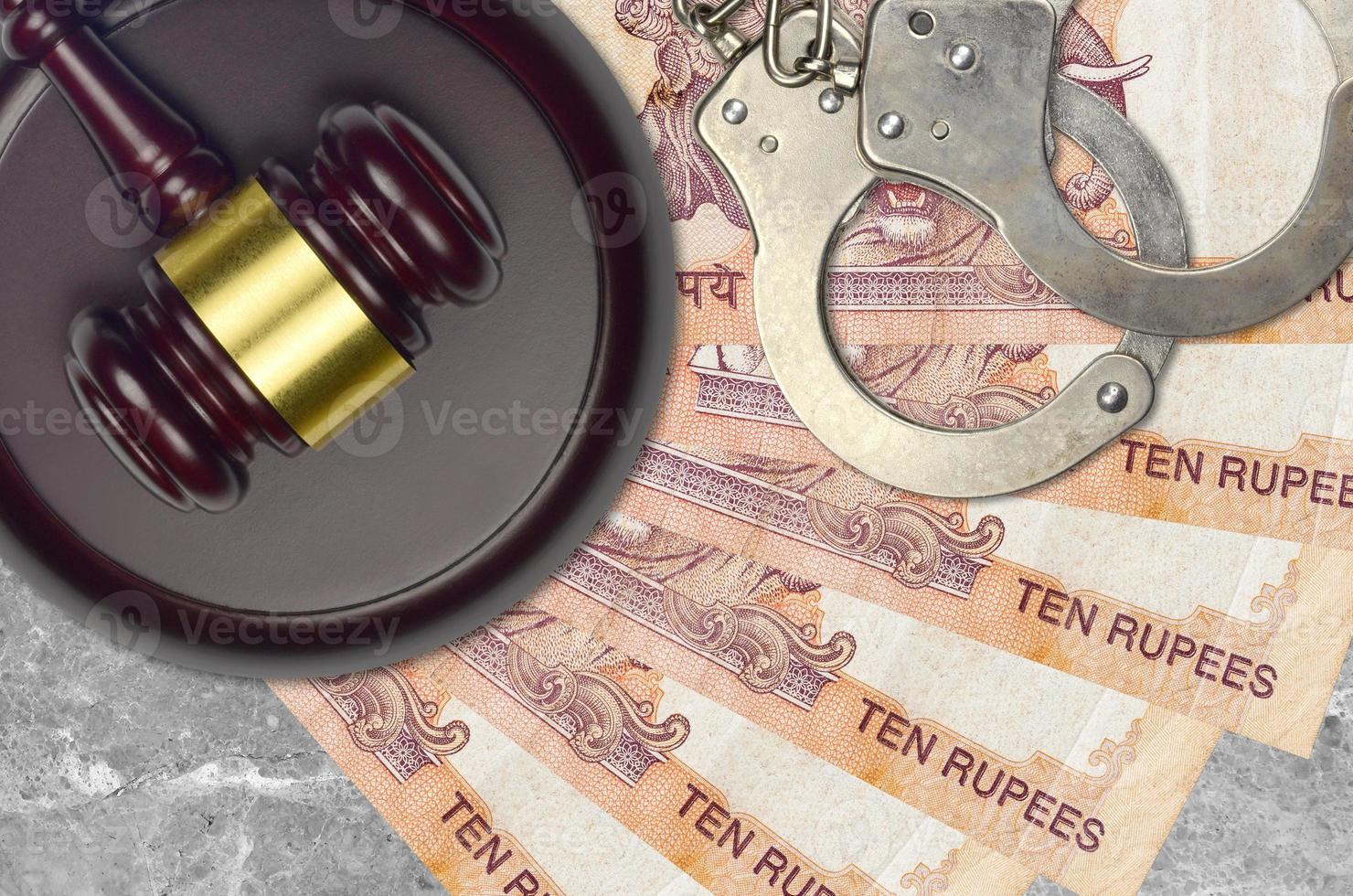 10 Indian rupees bills and judge hammer with police handcuffs on court desk. Concept of judicial trial or bribery. Tax avoidance photo