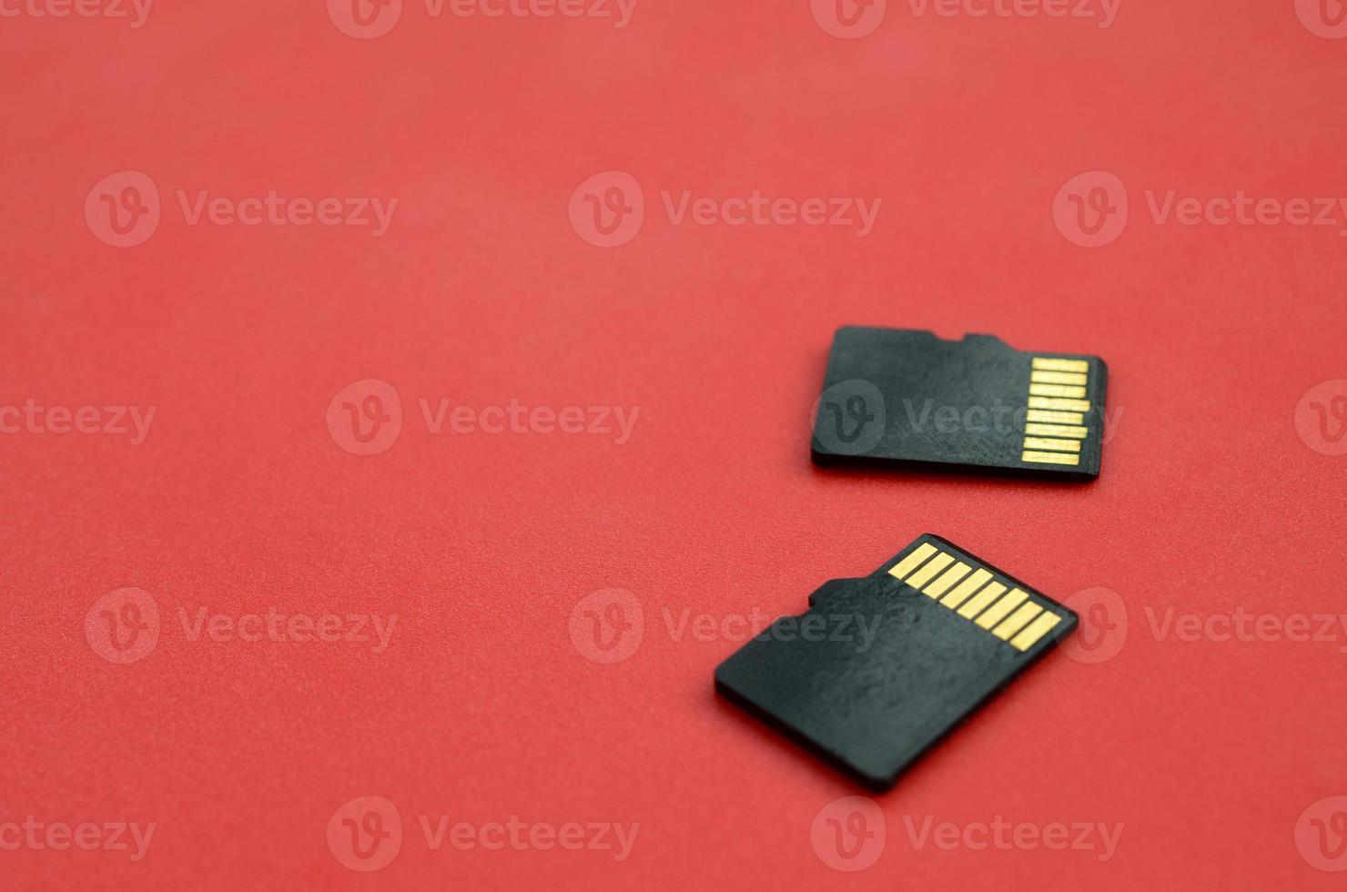 Two small micro SD memory cards lie on a red background. A small and compact data and information store photo