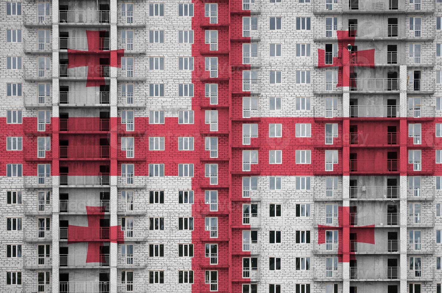 Georgia flag depicted in paint colors on multi-storey residental building under construction. Textured banner on brick wall background photo
