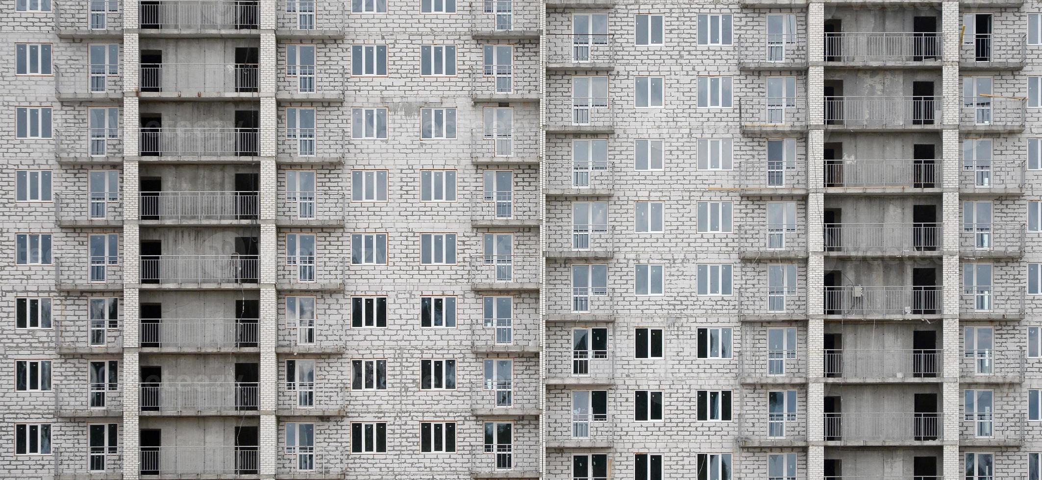 patrón texturizado de una pared de construcción de casas residenciales de piedra blanca rusa con muchas ventanas y balcón en construcción foto