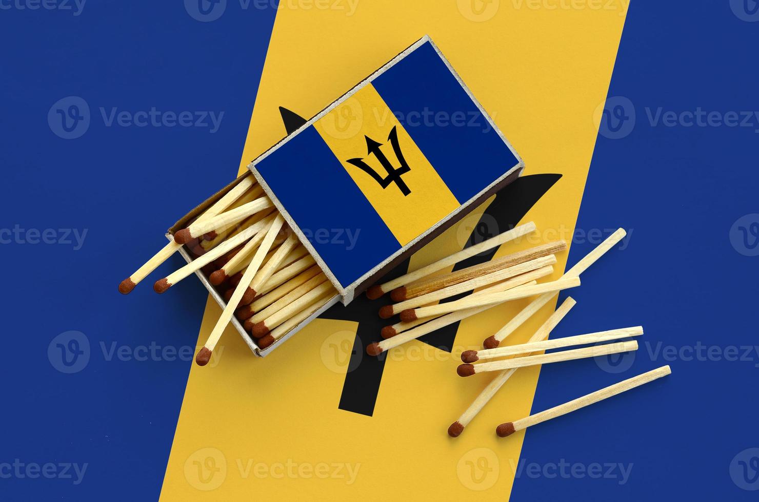 Barbados flag is shown on an open matchbox, from which several matches fall and lies on a large flag photo
