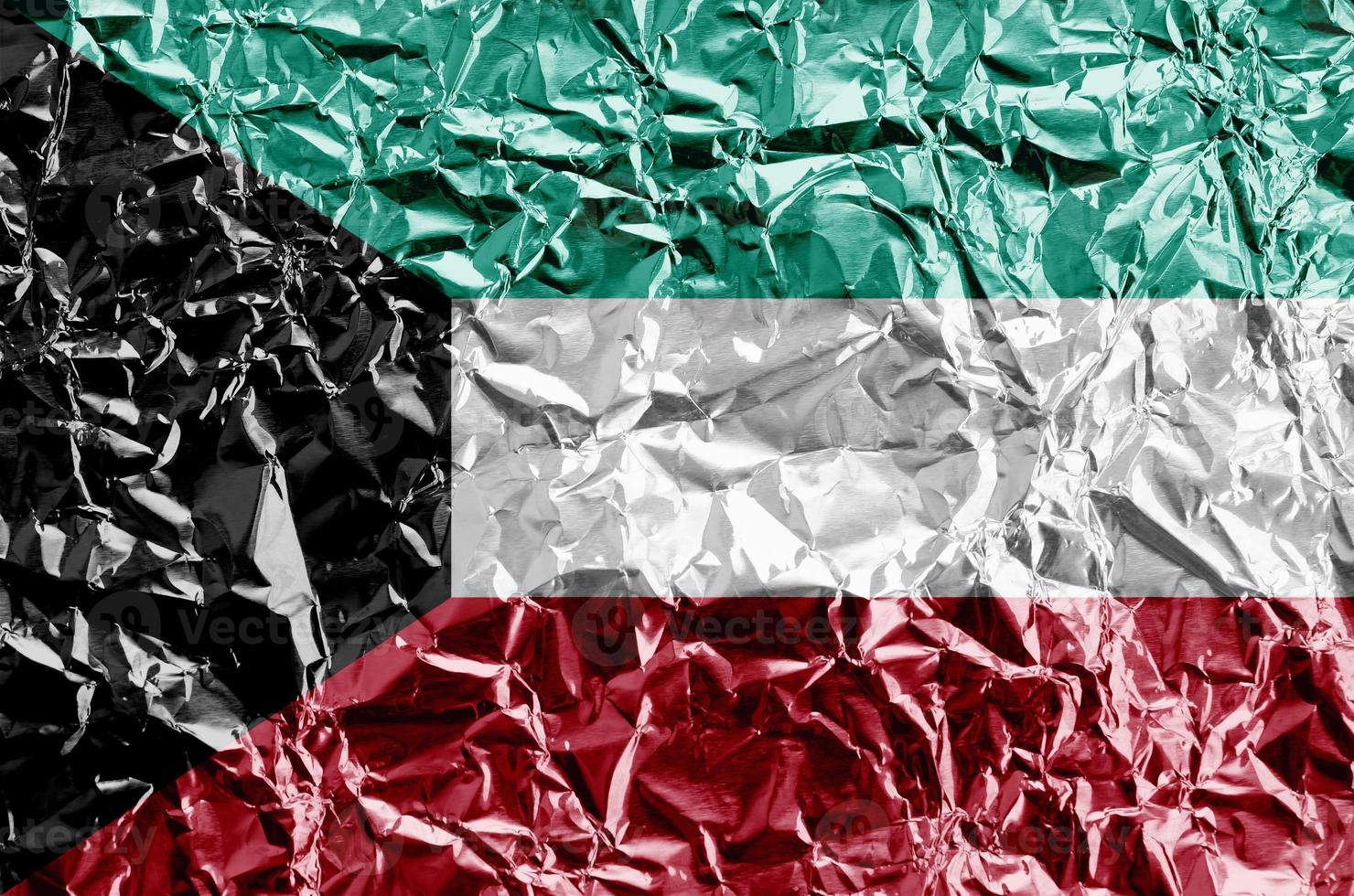 Kuwait flag depicted in paint colors on shiny crumpled aluminium foil closeup. Textured banner on rough background photo