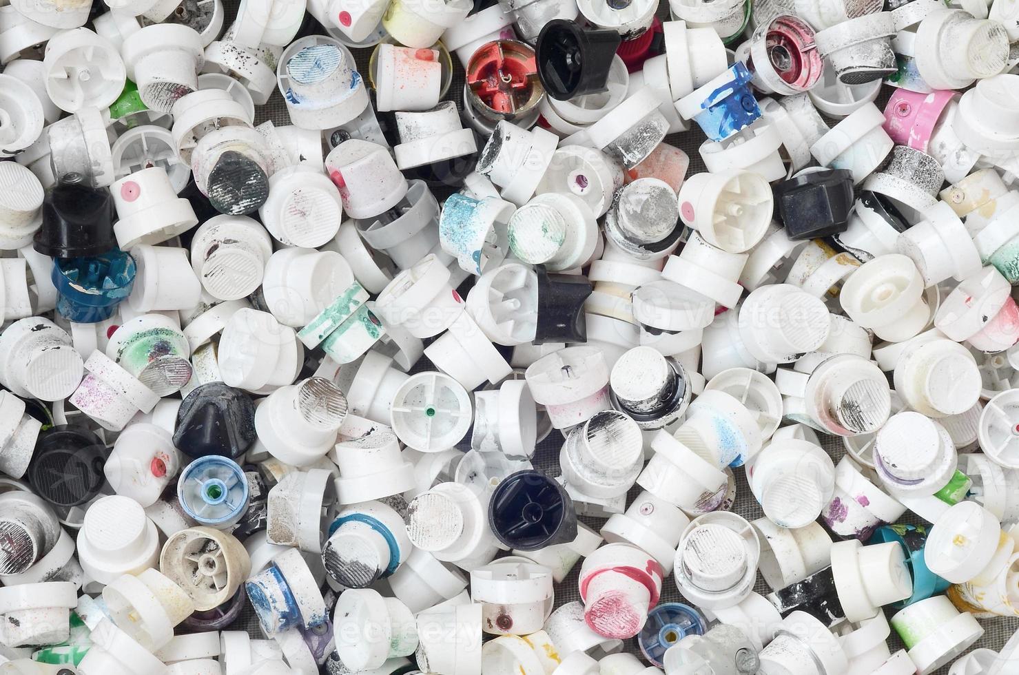 A pattern of many used and soiled nozzles from spray cans with aerosol paint. Background texture of the street art of drawing graffiti on the walls photo