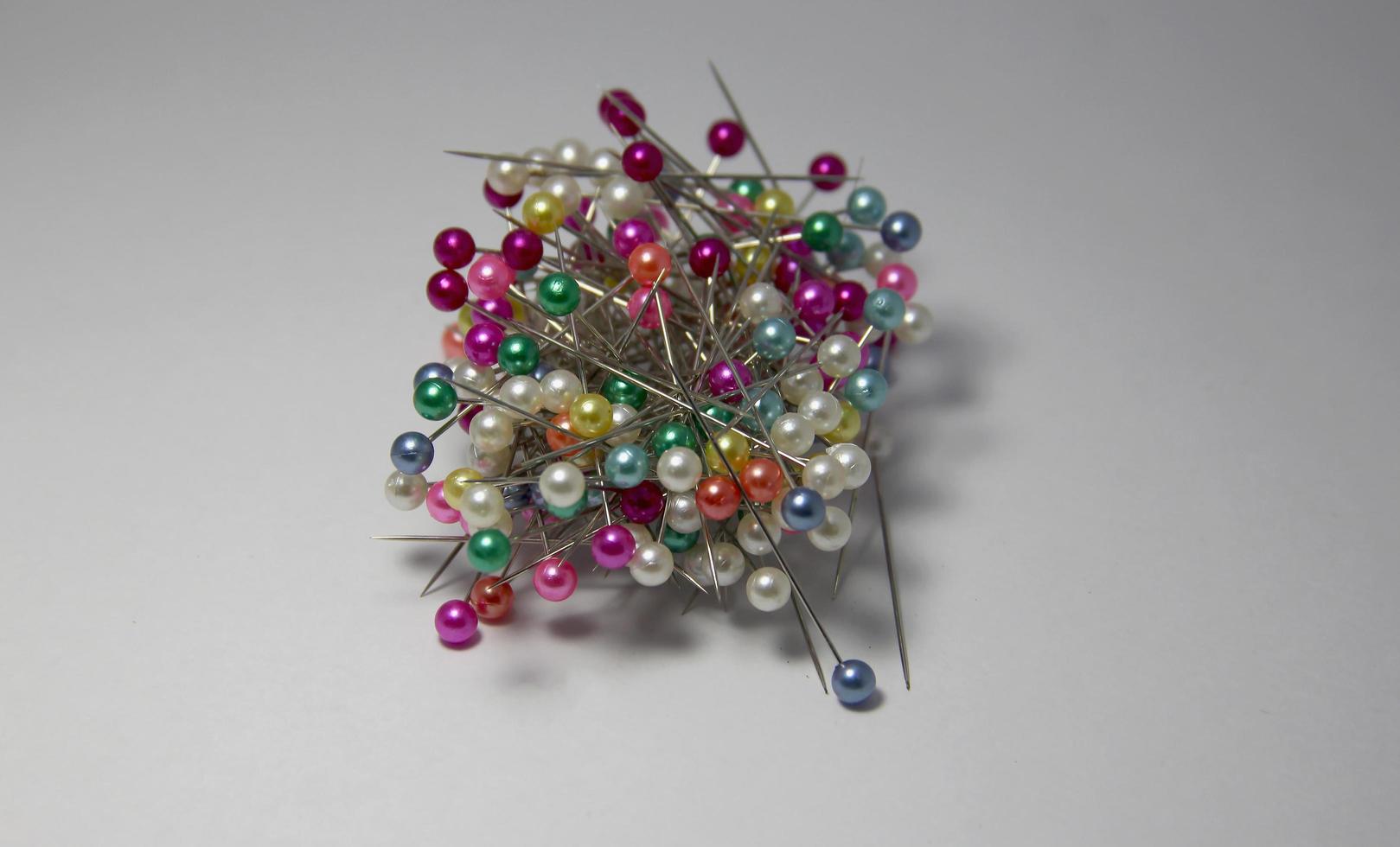Many multicolored straight push needles pin photo isolated on white plain background. Multiple sewing and tailor garments equipment tools intersecting with each other in the middle of the photo.