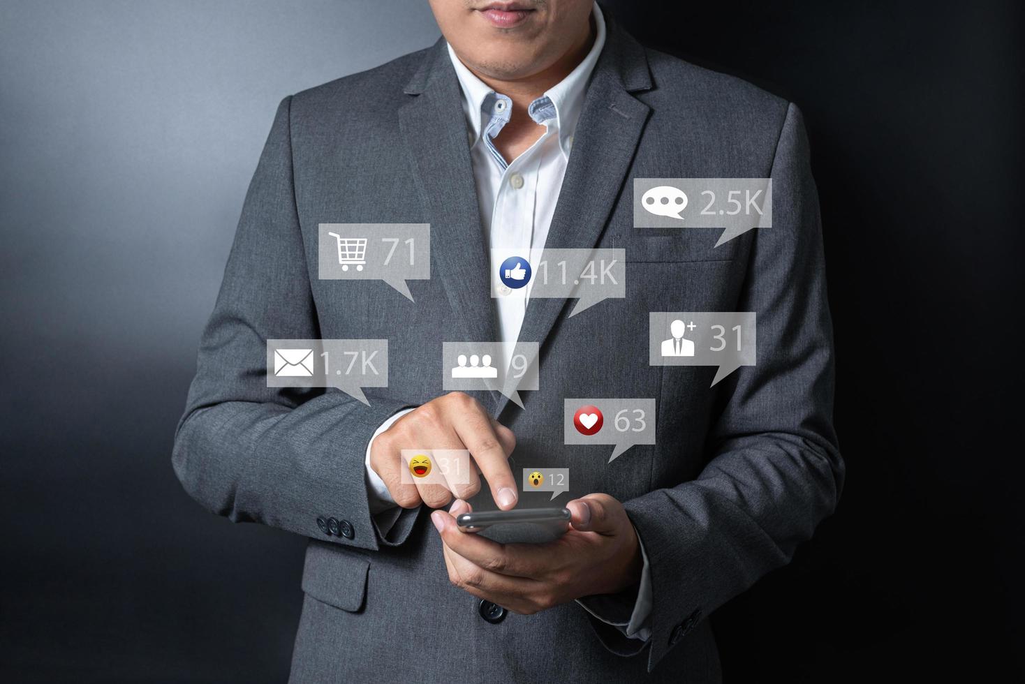 Close up businessman pushing, touching on smartphone with virtual emotion icon on black and gray background photo