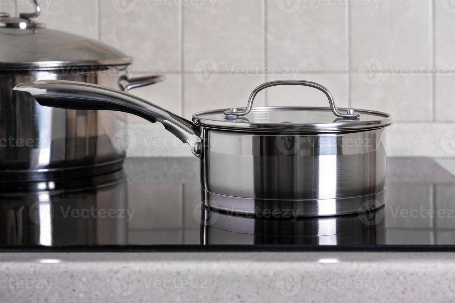 Ladle and large saucepan stand on modern stove with a glass-ceramic hob photo