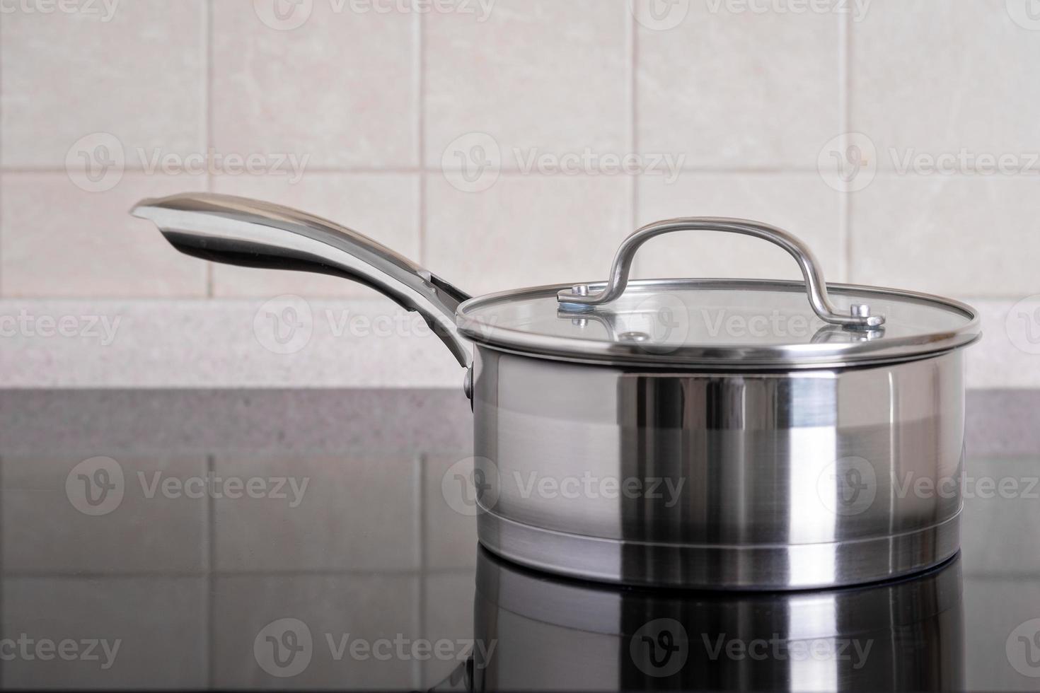 Stainless steel ladle sits on modern stove with glass-ceramic hob. photo