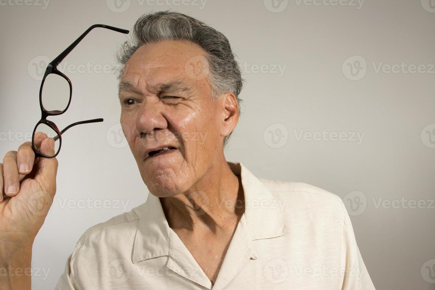 Mature man cleaning and checking his eye glasses to see if there clean photo