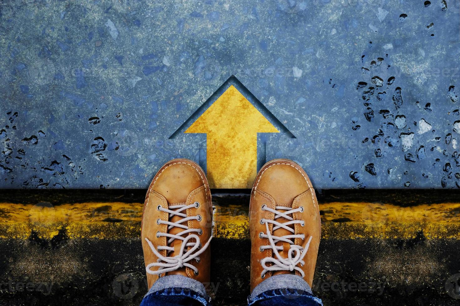 concepto de motivación y éxito. vista superior del hombre con zapatos de cuero sentado en la encrucijada para tomar la decisión de dar pasos o detenerse. flecha hacia adelante en el suelo como fondo foto