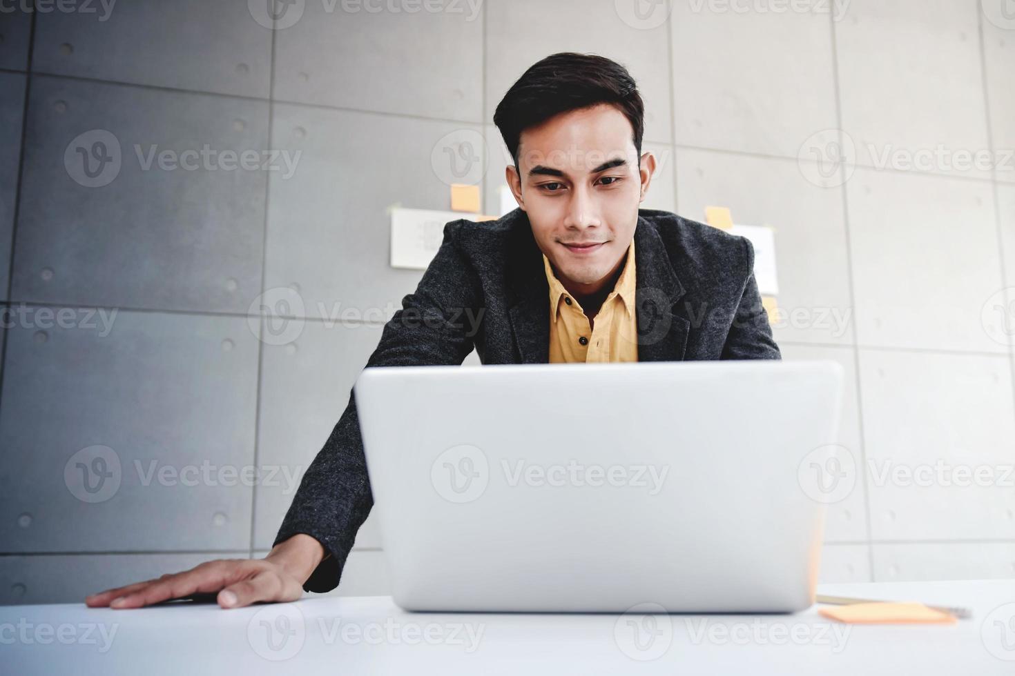 Happy Young Asian Businessman Working on Computer Laptop in Office photo