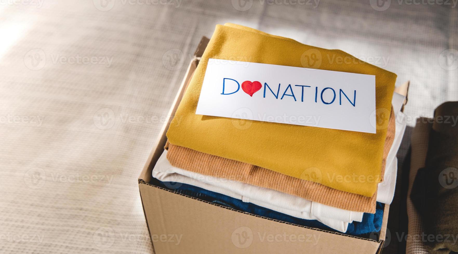 Clothes Donation Concept. Box of Cloth with Donate label. Preparing Used Old Garment at Home. Top View photo