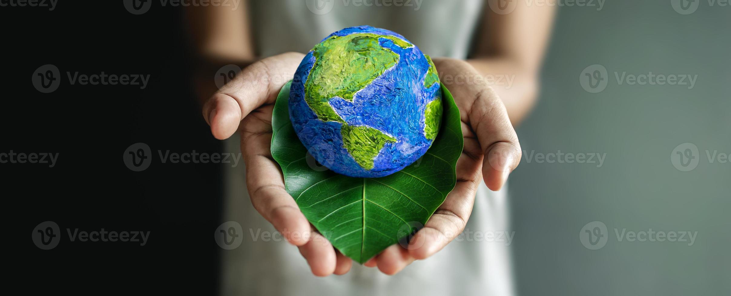 concepto del día mundial de la tierra. energía verde, recursos renovables y sostenibles. cuidado del medio ambiente y la ecología. mano abrazando hoja verde y globo hecho a mano foto