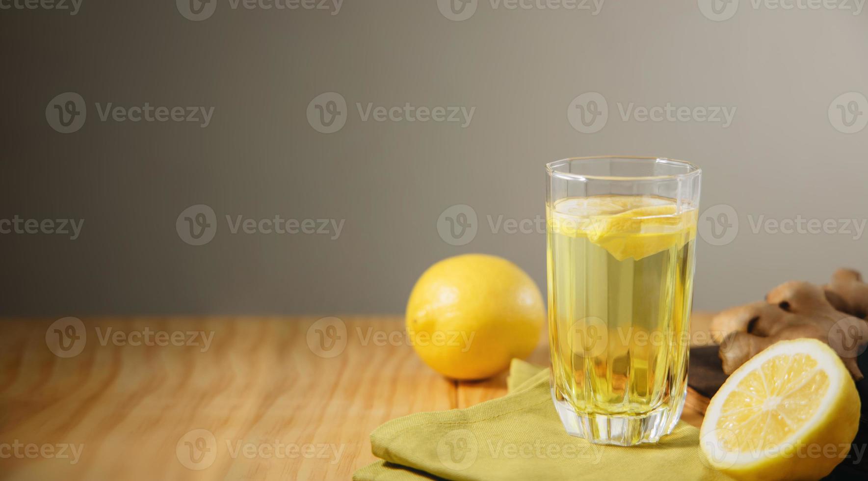 vaso de bebida de infusión de jengibre y limón. estilo de vida orgánico y saludable. agua dulce con rodajas de limón. presente en mesa con luz natural. bebida de temporada foto