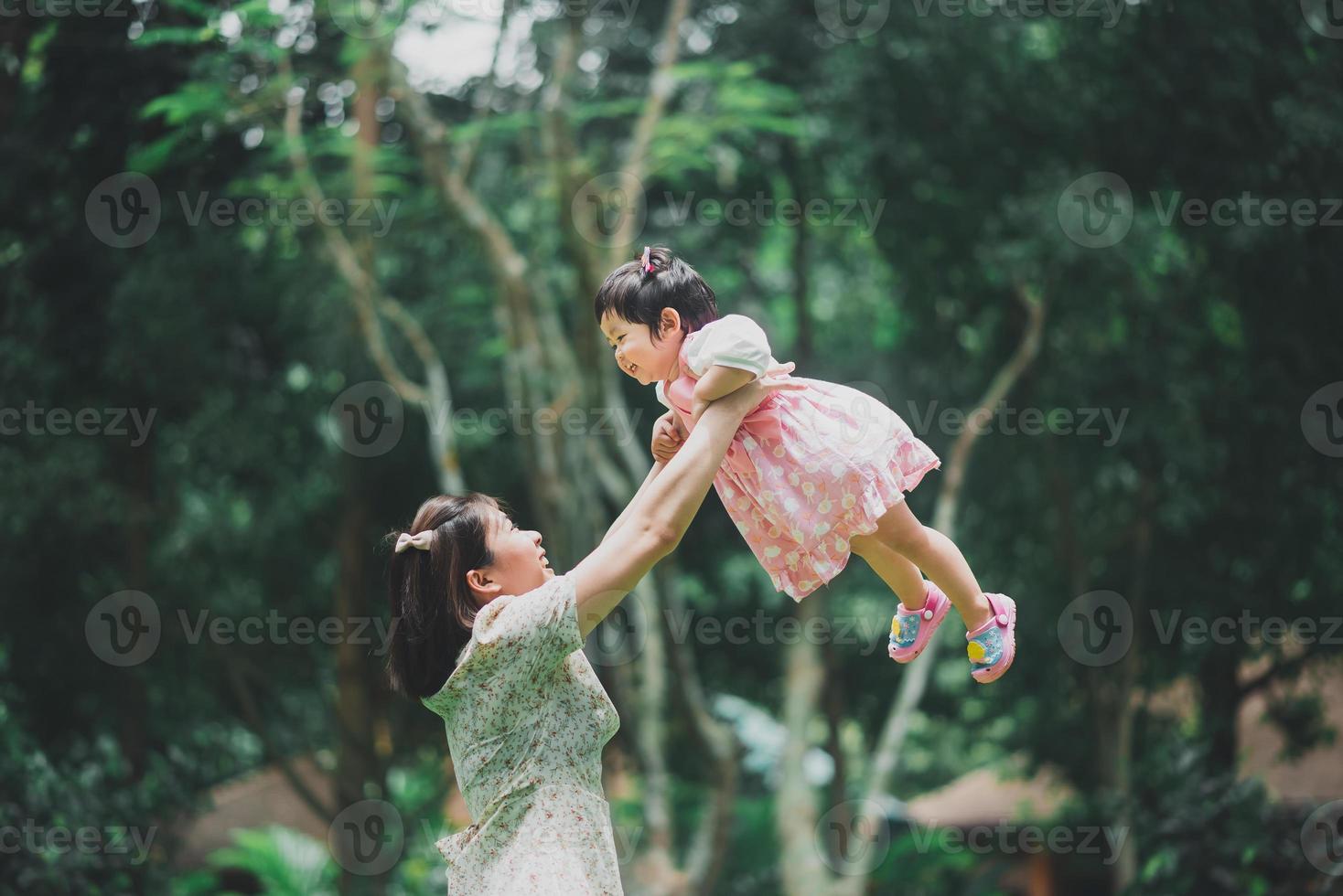 Asian enjoy happy mother mom holding his daughter and having good time in autumn park. Concept of family. Father and child daughter. Happy family. photo