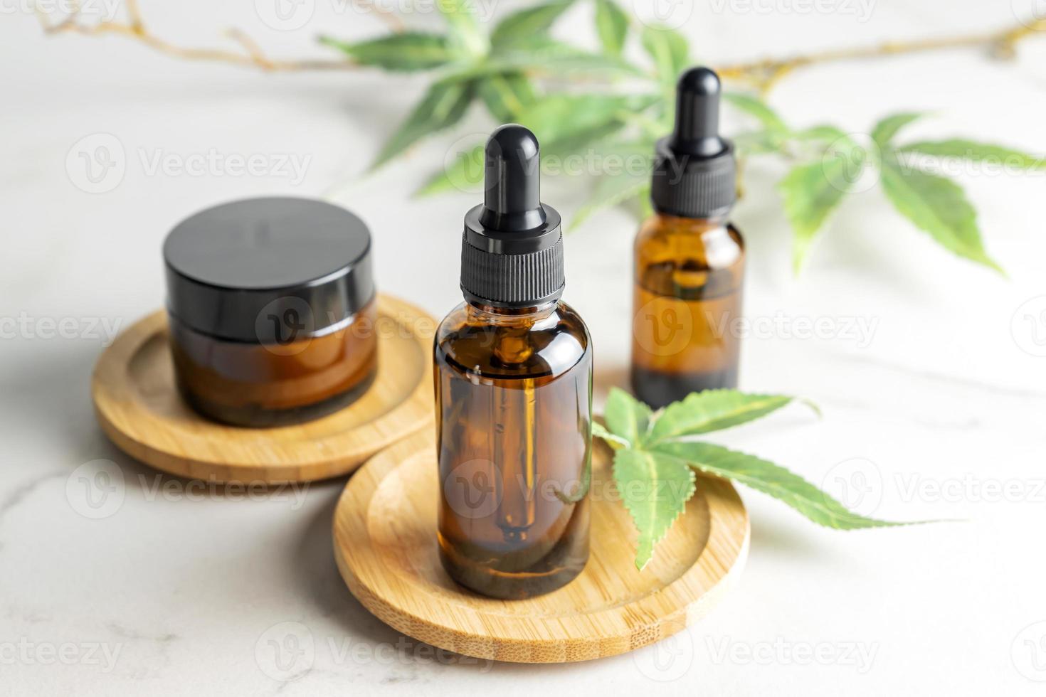 Cannabis face care cosmetics - cream, serum and oil dropper concept. Natural cosmetic. CBD oil, THC tincture and hemp leaves on a marble background photo