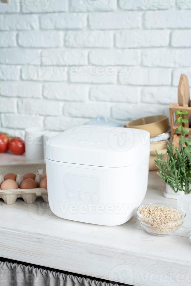 Electric rice cooker on wooden counter-top in the kitchen photo