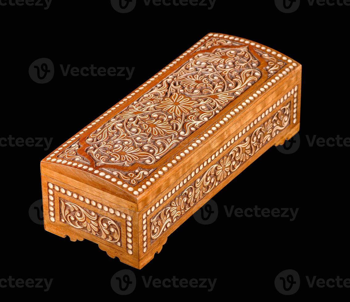 A wooden casket with traditional artistic carving isolated on a black background photo