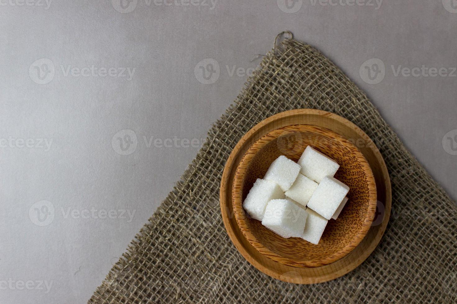 cubos de azúcar en platos de madera sobre tela de saco en la mesa de la cocina. vista superior. con espacio de copia foto