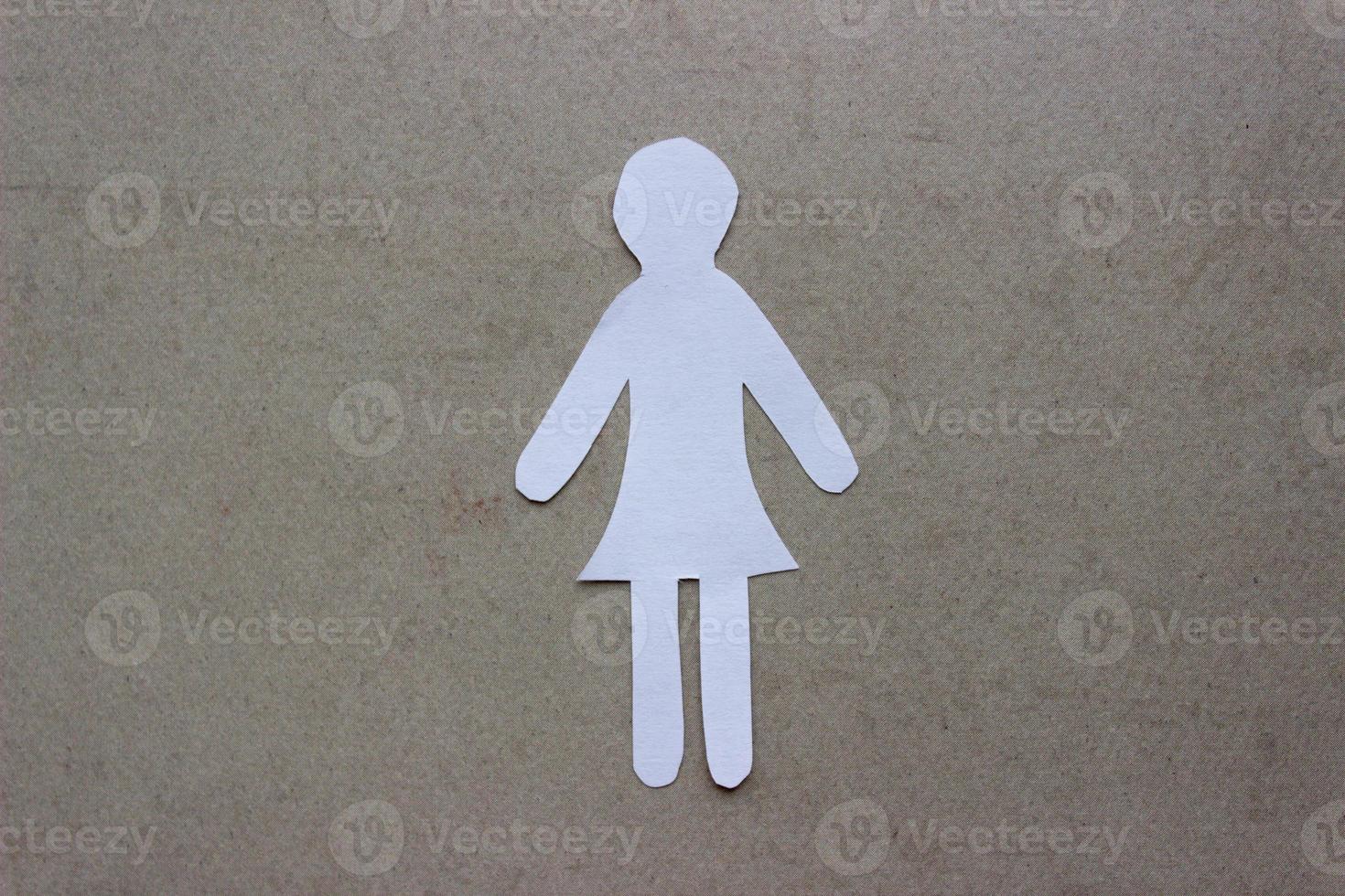 Silhouette of a woman in dress of white paper, cut by hand. In the center of the photo on beige background