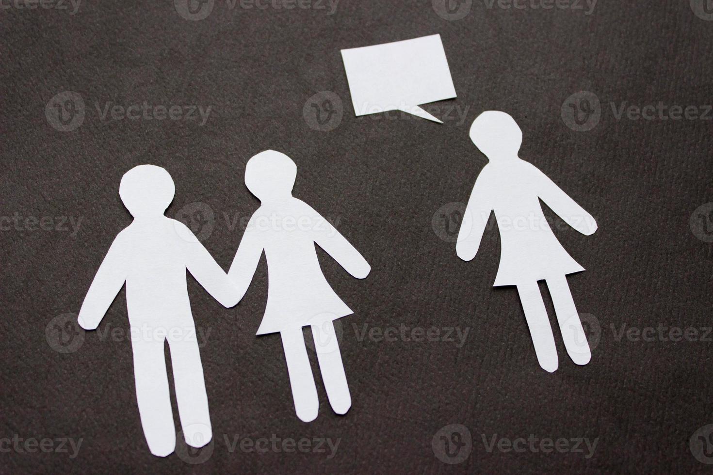 Silhouettes of people cut from paper. Couple holding hands and next to a lonely woman with speech-bubble over her. The concept of relationships, love, jealousy, loneliness, treason photo