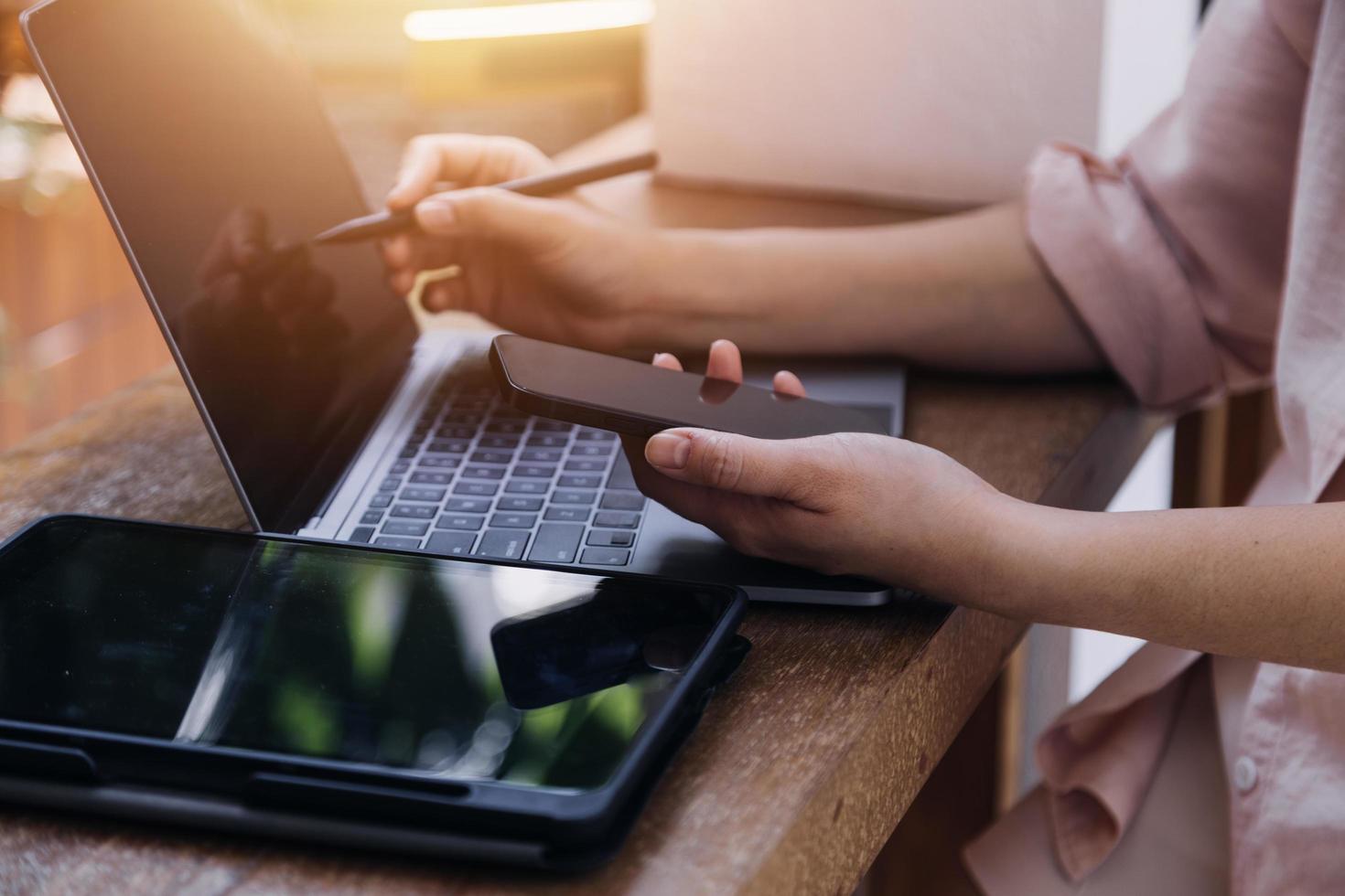 mano de mujer de negocios trabajando con computadora portátil, tableta y teléfono inteligente en la oficina moderna con diagrama de icono virtual en la oficina moderna a la luz de la mañana foto