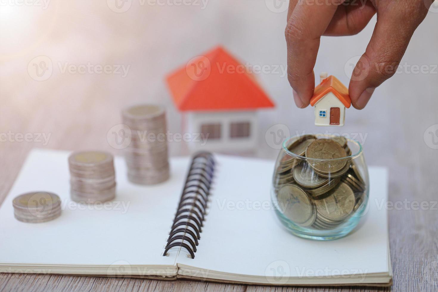 A woman holding a house on a pile of coins is planning savings money. concept for property ladder, mortgage and real estate investment. for saving or investment for a house. photo