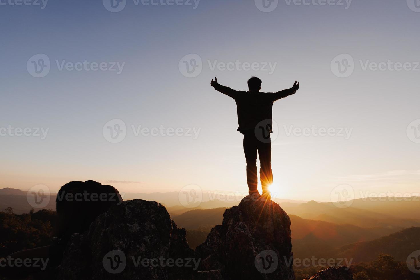 la silueta del hombre sube la mano en la cima de la montaña y el fondo abstracto del cielo del atardecer. concepto de libertad y aventura de viaje. rezar o rezar, recordar a dios, copiar espacio. foto