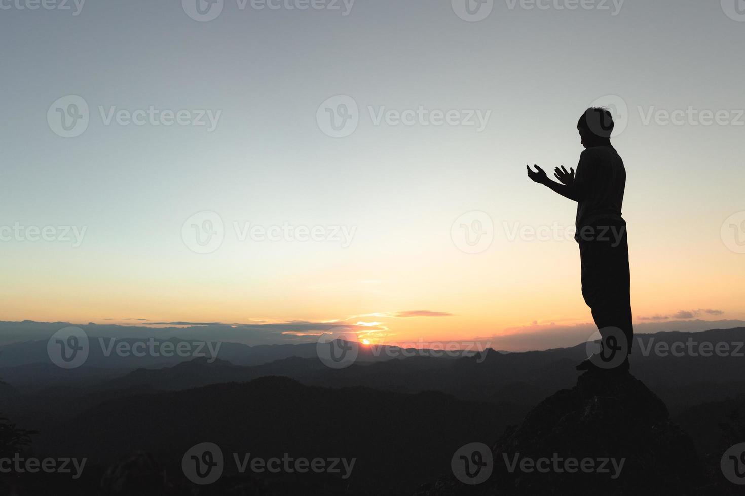 hombre rezando en las montañas al atardecer, concepto de vacaciones al aire libre armonía con el paisaje natural, estilo de vida de viaje relajación espiritual meditación emocional. foto