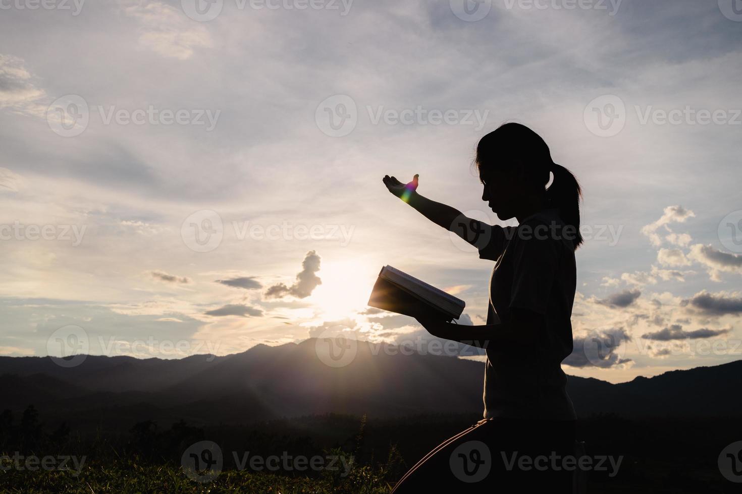 silueta de una joven religiosa rezando a dios por la mañana, espiritualidad y religión, cristianos y concepto de estudio bíblico. foto