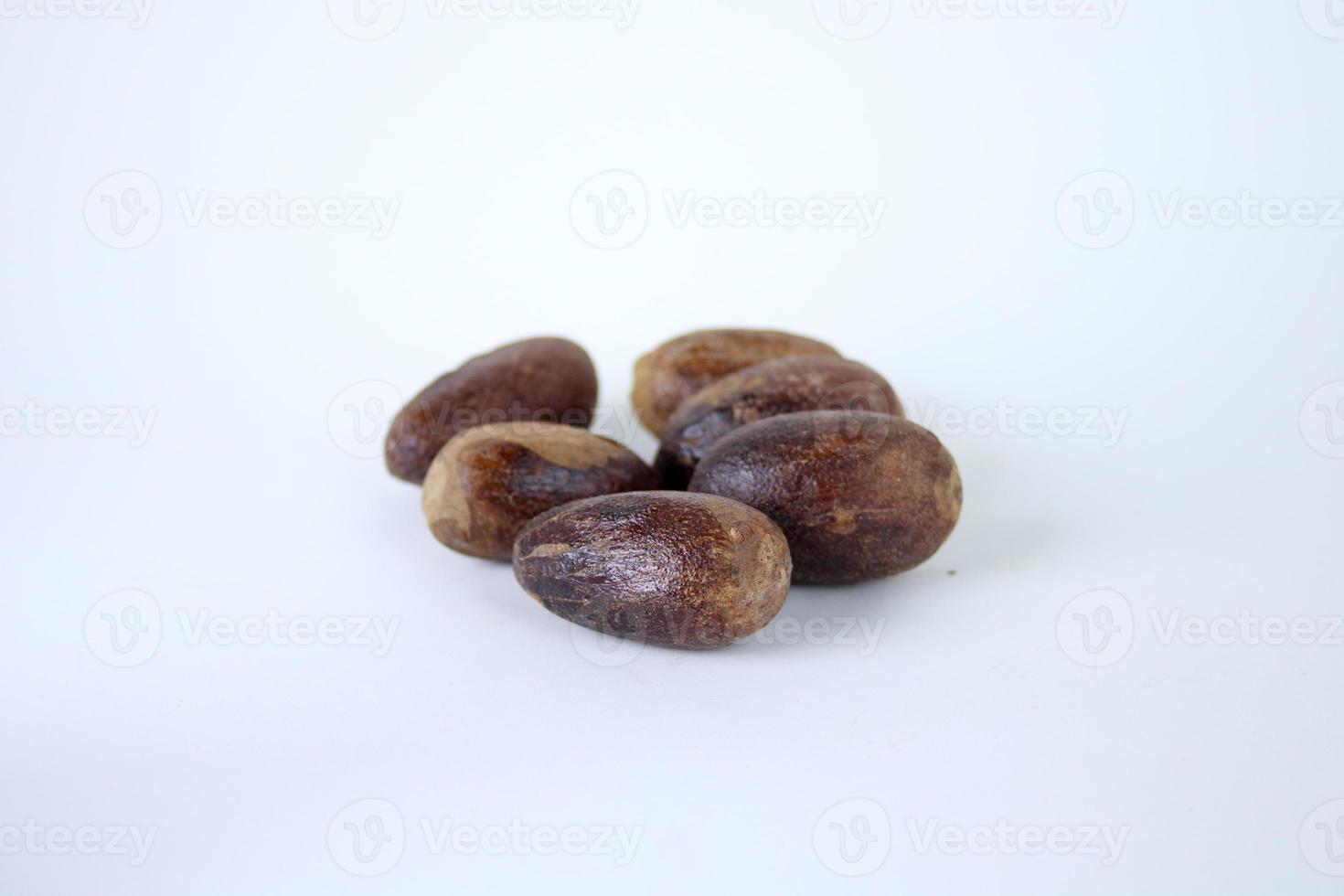 Dark brown whole seeds of nutmeg and white background. photo