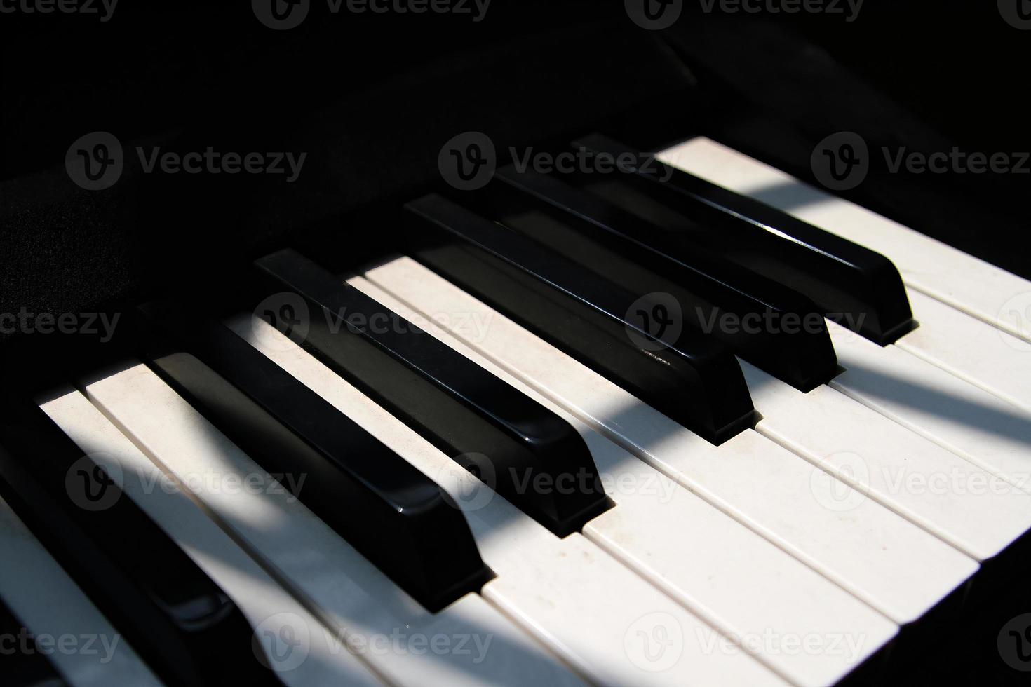 Close up view of piano keyboard near window with shadow overlay effect. Piano key sunny effect. Electric piano keyboards in four-line octave. White keys and black keys. Piano sunlight wallpaper art photo